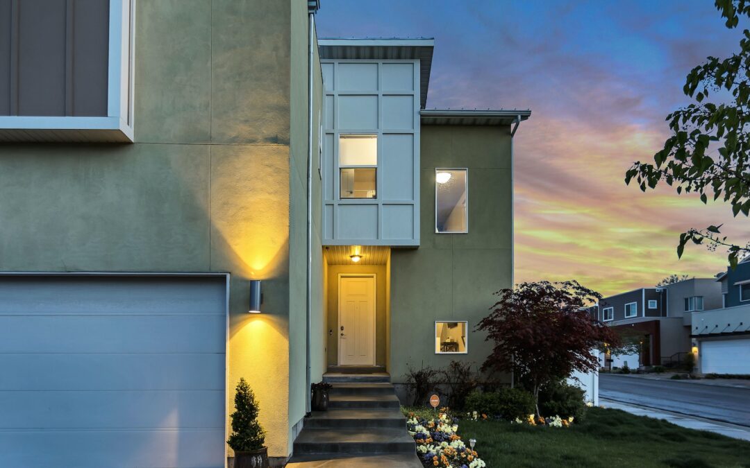 Modern home with well lit exterior and landscaping along the entryway